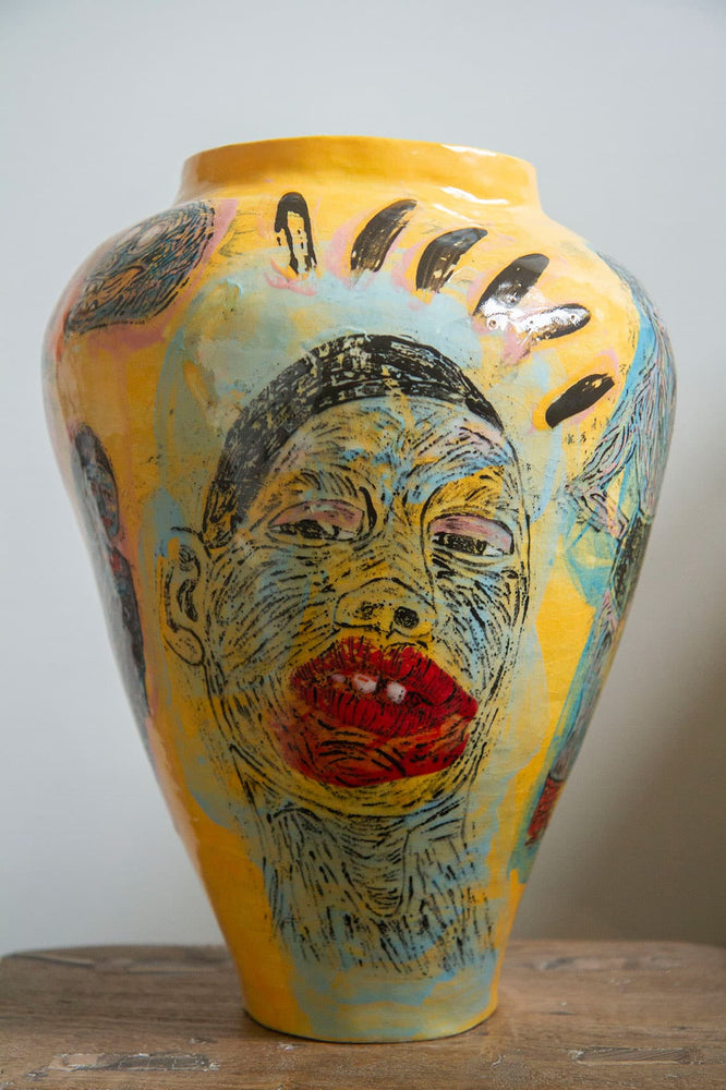 Large yellow ceramic vase decorated with a hand painted image of a woman's face 