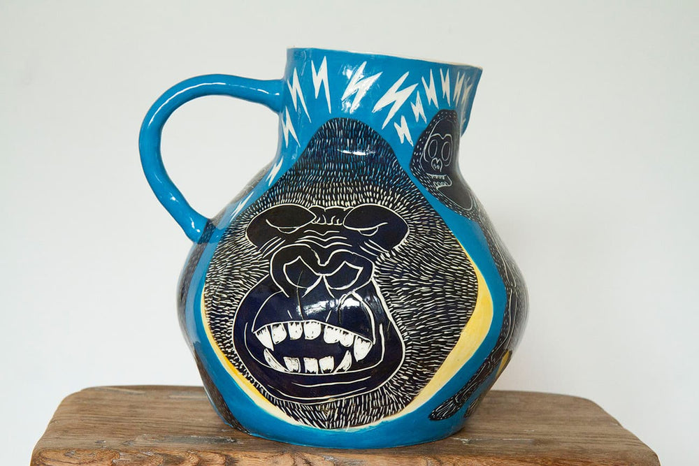 Blue ceramic jug decorated with an angry gorilla face. 