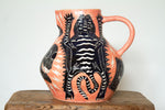 A pink ceramic jug decorated with an image of a black and white tiger and skull