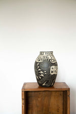 Black and white ceramic vase with a sgraffito design of a skeleton